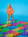 Action figure stand on colorful plastic number and hold orange plastic number tow on blue background. Concept of education mathema