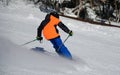 Action photo of skier in bright outfit going down the slope leaving fresh powder snow behind. Royalty Free Stock Photo