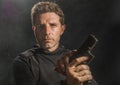 Action portrait of serious and attractive hitman or special agent man holding gun reloading the weapon on dark background