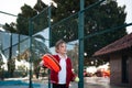 An action shot of a child reaching high to serve a padel tennis ball on an outdoor court, with palm trees in the Royalty Free Stock Photo