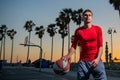 Action shot of young man playing basketball outdoors.