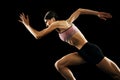 Studio shot of young muscular woman running isolated on black background. Sport, track-and-field athletics, competition Royalty Free Stock Photo