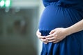 Action of a woman in blue dress is hugging with baby in her belly. Royalty Free Stock Photo