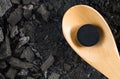 Activated carbon pill medicine in wooden spoon on ground charcoal