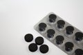 Activated charcoal round black tablets pills and blister on white background Royalty Free Stock Photo