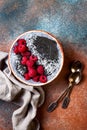 Activated charcoal smoothie and chia seed pudding bowl, vegan detox dessert with raspberry and coconut milk. Overhead, top view