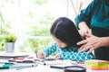 A cute little Asian girl is drawing and coloring, and the mother does her hair. Royalty Free Stock Photo