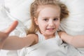 Active adorable child awake, soft white sheets Royalty Free Stock Photo