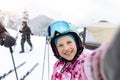 Active adorable school caucasian kid girl portrait enjoy have fun making selfie photo skiing in helmet, goggles winter