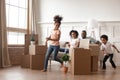 Active african kids running around boxes laughing on moving day Royalty Free Stock Photo