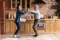 Active aged family couple cooking dancing at modern wooden kitchen