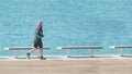 Active ageing of the elderly though the marina next to se beack. Outdoors running and sport workout against a blue sea.