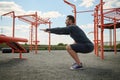 Active athlete in athletic uniform performing squats during training on an outdoor sports field. Young man doing sports on the