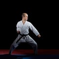 Active athlete does formal karate exercises on red and blue tatami