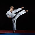 Active athlete trains formal karate exercises on red and blue tatami