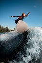 Active athletic young woman in wetsuit stands on surfboard and rides on the wave.