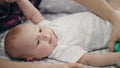 Active baby lying on back in bed. Adorable baby boy trying overturn