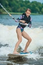 Active beautiful girl in the swimsuit standing on the wakeboard in the river Royalty Free Stock Photo