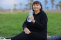 Active beautiful senior woman resting holding water bottle after yoga, work out exercising for health in the park on Royalty Free Stock Photo