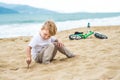 Active blond kid boy and bicycle near the sea. Toddler child dreaming and having fun on warm summer day. outdoors games for childr Royalty Free Stock Photo
