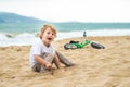 Active blond kid boy and bicycle near the sea. Toddler child dreaming and having fun on warm summer day. outdoors games for childr Royalty Free Stock Photo