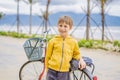 Active blond kid boy driving bicycle in the park near the sea. Toddler child dreaming and having fun on warm summer day Royalty Free Stock Photo