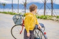 Active blond kid boy driving bicycle in the park near the sea. Toddler child dreaming and having fun on warm summer day Royalty Free Stock Photo