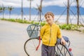 Active blond kid boy driving bicycle in the park near the sea. Toddler child dreaming and having fun on warm summer day Royalty Free Stock Photo