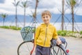 Active blond kid boy driving bicycle in the park near the sea. Toddler child dreaming and having fun on warm summer day Royalty Free Stock Photo