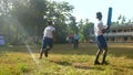 Active boy with blue cricket bat throws ball to schoolmate