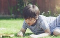 Active boy lying on grass playing with soldiers and tank toys in the garden, Kid talking with him self while play wars and peace