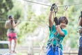 Active brave boy enjoying outbound climbing at adventure park on