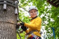 Active brave little boy enjoying climbing at treetop adventure park