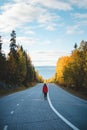 Active brunette traveller in a red jacket finds her own way through life. A 20-year-old explorer walks along the main road through Royalty Free Stock Photo