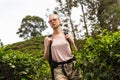 Active caucasian blonde woman enjoing fresh air and pristine nature while tracking among tea plantaitons near Ella, Sri