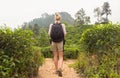 Active caucasian blonde woman enjoing fresh air and pristine nature while tracking among tea plantaitons near Ella, Sri