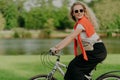 Active Caucasian curly woman looks aside, rides sport bicycle, covers distance and travels in open air, dressed in casual clothes Royalty Free Stock Photo