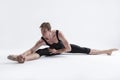 Active Caucasian Relaxed Ballerino Dancer Sitting While Practising Stretching Legs and Body Exercices In Black Sportive Tights in