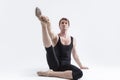 Active Caucasian Relaxed Ballerino Dancer Sitting While Practising Stretching Legs Exercices In Black Sportive Tights in Studio