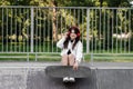 Active child girl with skate board and listen to music with headphones and sitting on skate playground and smile