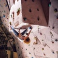 Active climber girl climbing up the wall