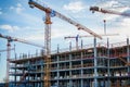 Active construction site with workers, machines, and scaffolding progressing.