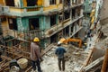 Active construction site with workers, machines, and scaffolding progressing.