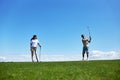 Active couple playing golf on field against blue sky Royalty Free Stock Photo