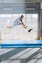 Active crazy guy is tryng to catch falling toy while jumping on the trampoline