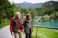 Active elderly couple hiking together in autumn mountains, holding hands. Senior tourists enjoying view on lake. Royalty Free Stock Photo