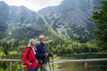 Active elderly couple hiking together in autumn mountains, on senior-friendly trail. Walking by lake, enjoying nature Royalty Free Stock Photo