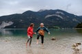 Active elderly couple hiking together in spring mountains, walking in cold water in mountain lake. Senior tourists