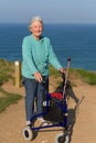 Active elderly lady pensioner in eighties with three wheel mobility frame by coast Royalty Free Stock Photo