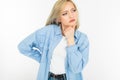 Active emotional blonde girl in jeans and a blue shirt standing against a white wall with copy space Royalty Free Stock Photo